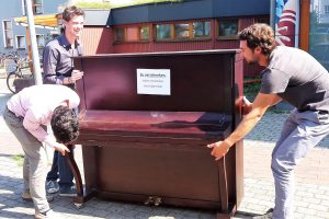 Am Wegesrand steht ein Klavier, und drei Cybus-Mitarbeiter nehmen es in Augenschein. Foto: Eimsbütteler Nachrichten