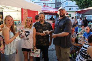 Beim Weinfest am Stand von Rindchen's Weinkontor haben Chrissy (ganz links) und Alexander (ganz rechts) mit ihrem Gewinn auf ihren Gewinn angestoßen. Foto: Eimsbütteler Nachrichten