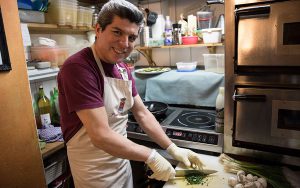 José schnippelt hygienisch korrekt mit Gummihandschuhen Zutaten für den Pizzabelag.Foto: Eimsbütteler Nachrichten