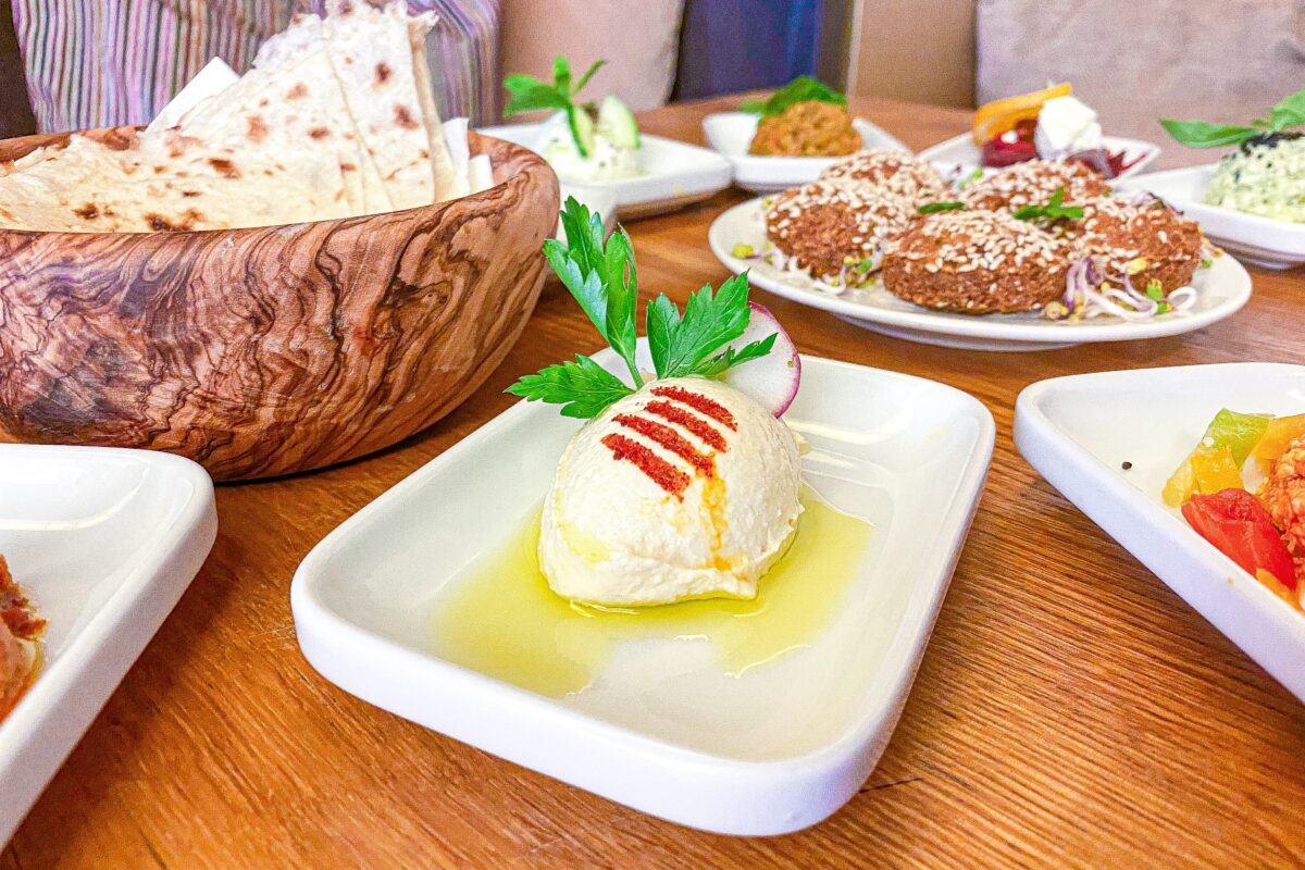 Im L'Orient bereitet Fadi Marouk Hummus zu und garniert ihn mit Petersilie und Olivenöl. Foto: Valentin Hillinger
