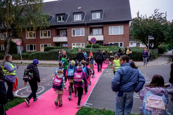 Kinder überqueren roten Teppich an der Randstraße. Foto: Aaron Müller